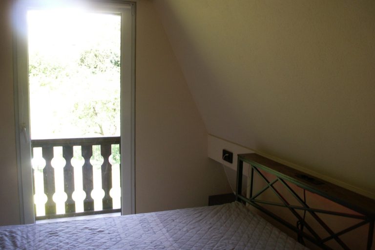 Schlafzimmer Ein helles Schlafzimmer mit einem Bett und einem Fenster zur Aussicht ins Freie.